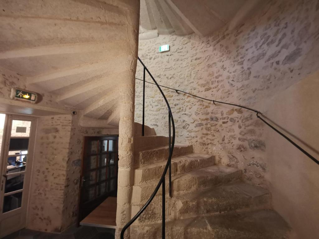 a staircase in a room with a stone wall at Le Relais du Chapeau Rouge in Saint Loup Lamaire