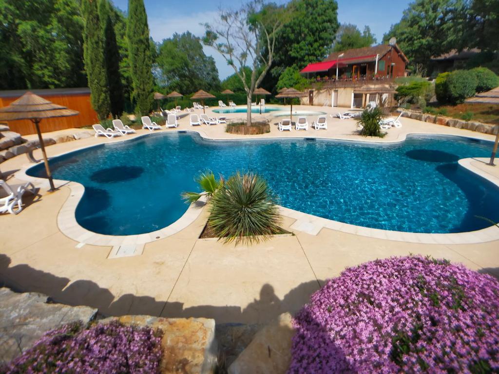 a large swimming pool with chairs and purple flowers at la Truffière Saint Cirq Lapopie in Saint-Cirq-Lapopie