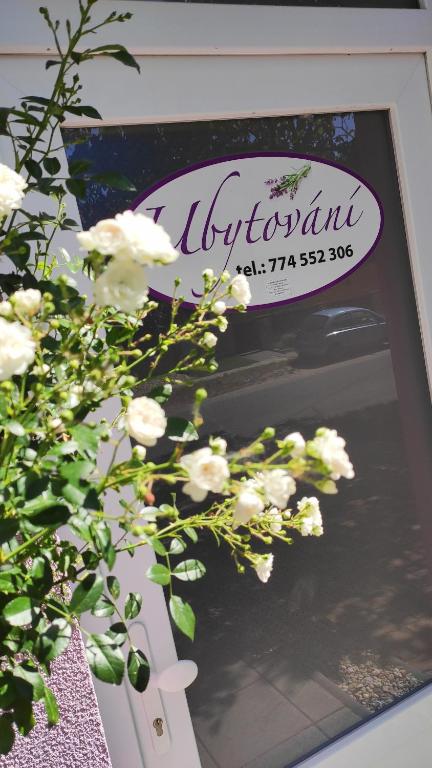 a sign on a window with white flowers in front at Apartmán Café u Kordulky in Ratíškovice