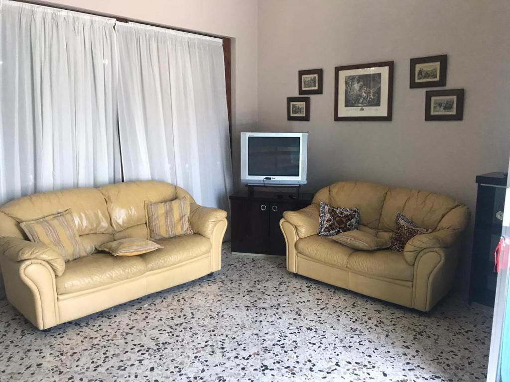 sala de estar con 2 sofás y TV en Sicilia confort, en Castellana Sicula