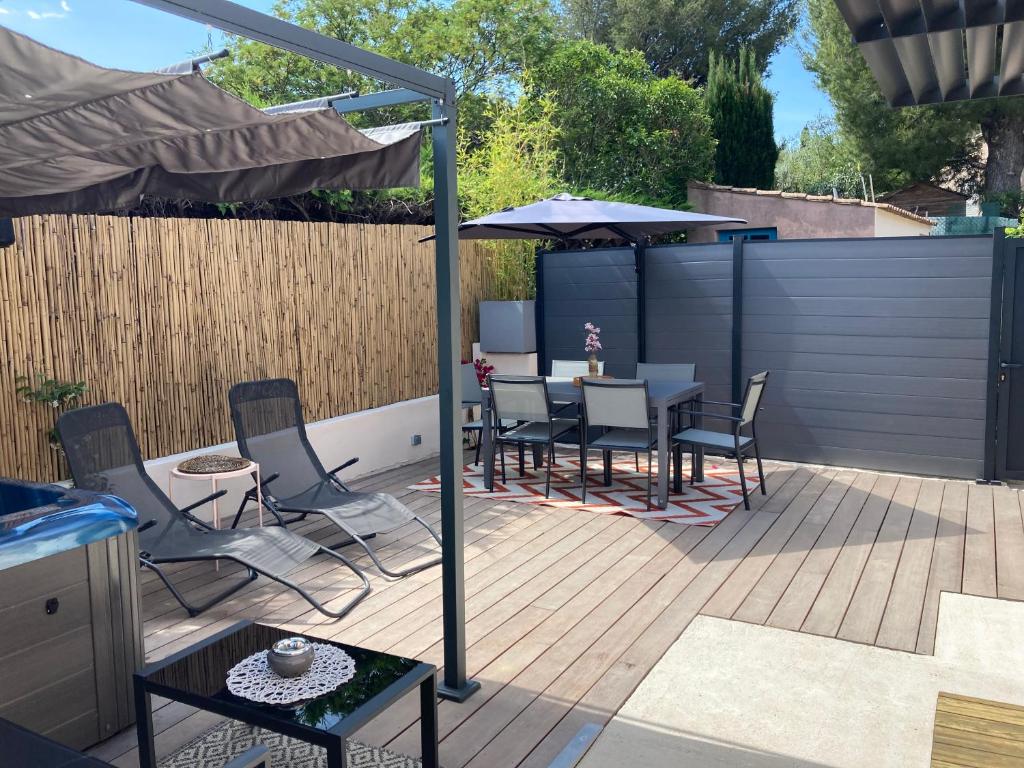 een patio met een tafel en stoelen en een parasol bij Villa Célina Accessible PMR in Sanary-sur-Mer