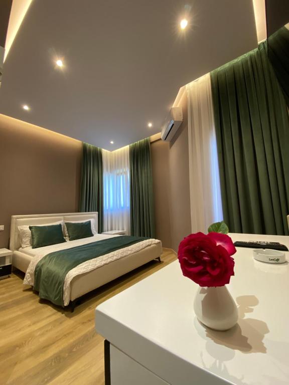 um quarto com uma cama e uma flor sobre uma mesa em Hotel Akropoli em Tirana