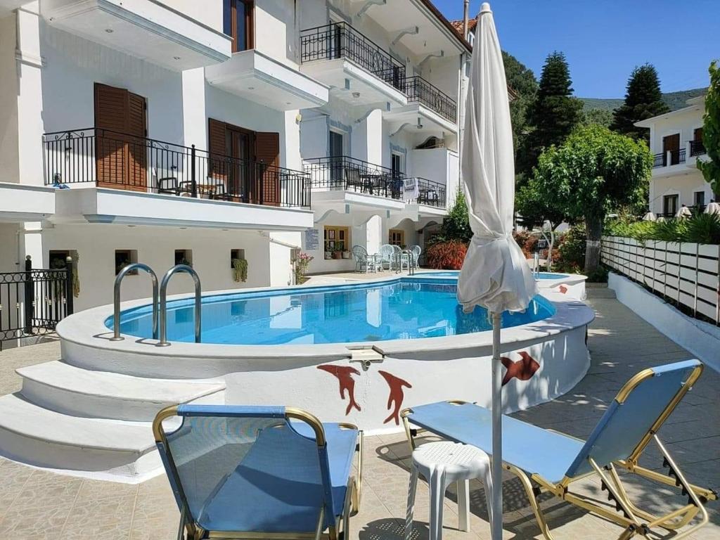 a pool in front of a building with chairs and an umbrella at Oasis in Parga
