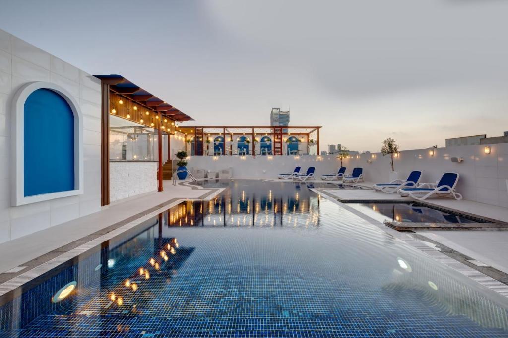a swimming pool with chairs and a building at Donatello Hotel in Dubai