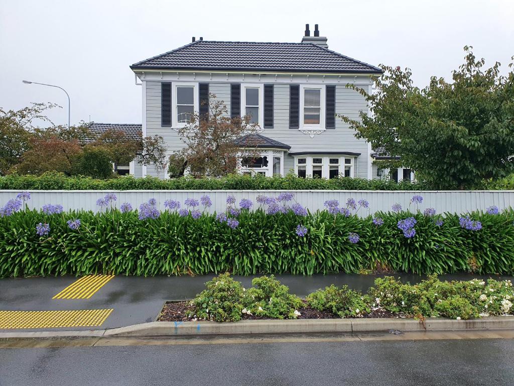 a white house with purple flowers in a garden at Dalkeith Boutique Bed & Breakfast in Kaiapoi