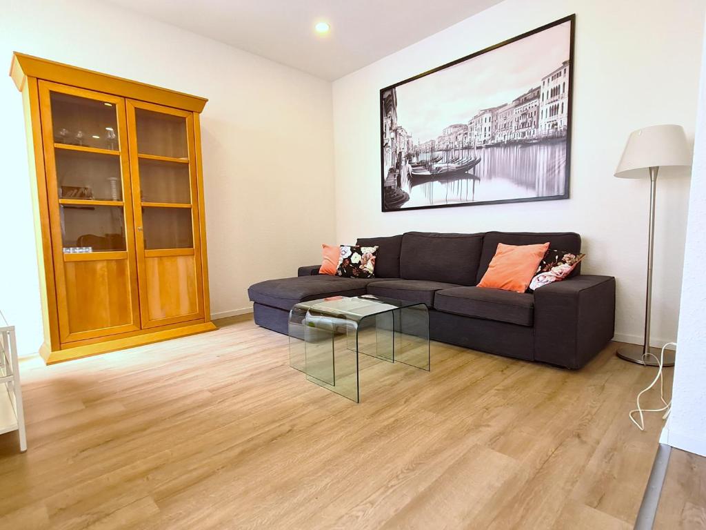 Burgunder - helle und ruhige Wohnung in Uninähe في ماينز: غرفة معيشة مع أريكة وطاولة زجاجية