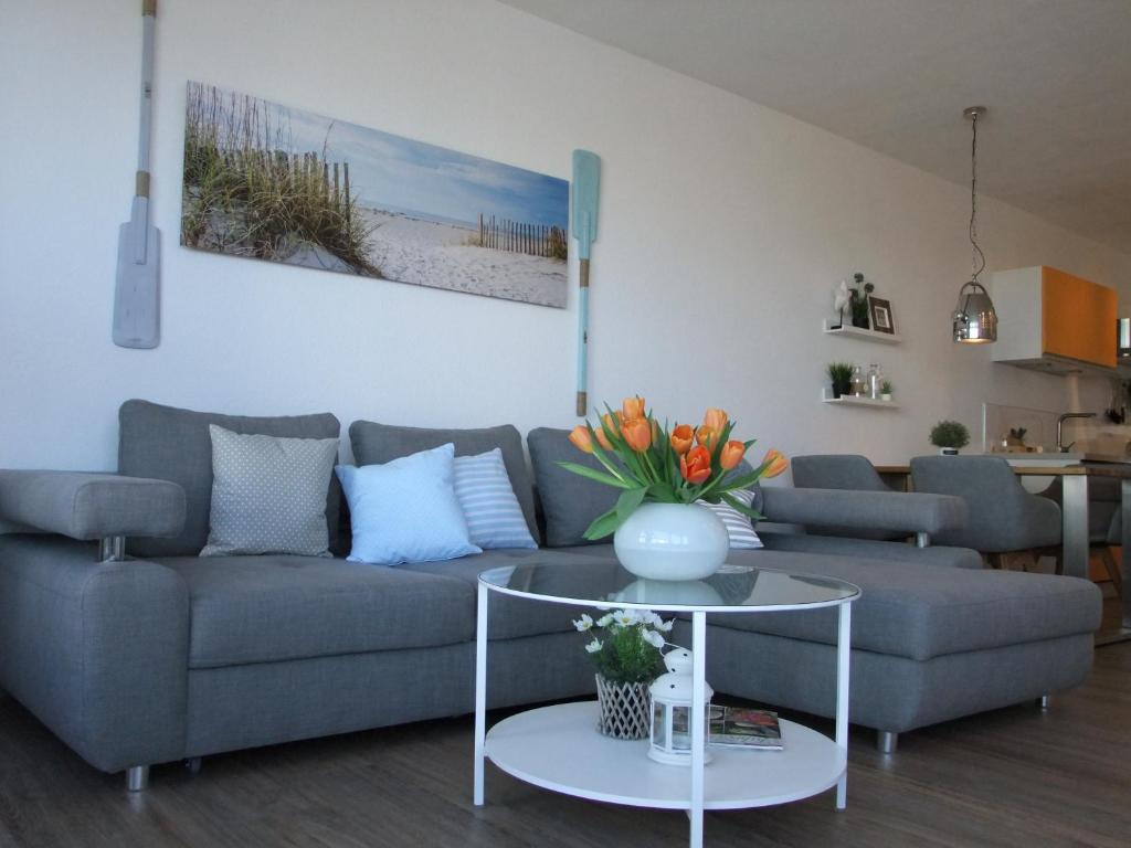 een woonkamer met een bank en een tafel met bloemen bij Ferienwohnung mit Seeischt im Haus Frische Brise 05.10 in Cuxhaven