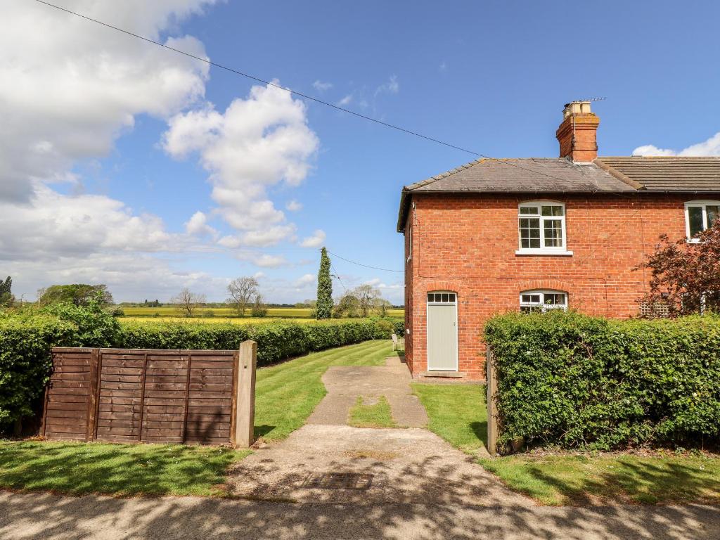 a brick house with a gate and a driveway at East Farm Cottage in Lincoln
