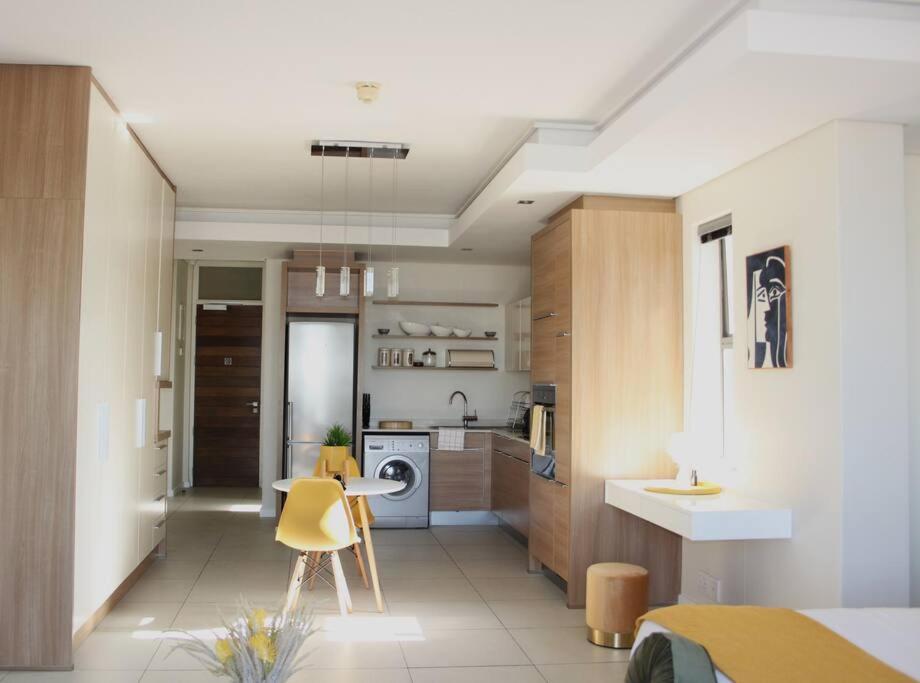 a kitchen with a yellow chair in a room at The crystal towers one-bedroom studio in Cape Town
