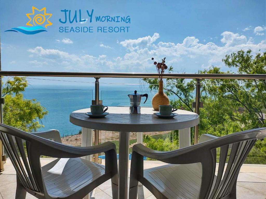 een tafel en 2 stoelen op een balkon met uitzicht op de oceaan bij July Morning Seaside Resort in Kavarna
