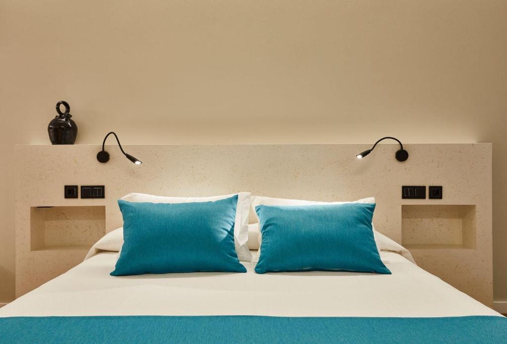 a large bed with two blue pillows on it at Hotel Boutique Molino de Enmedio in Huéneja