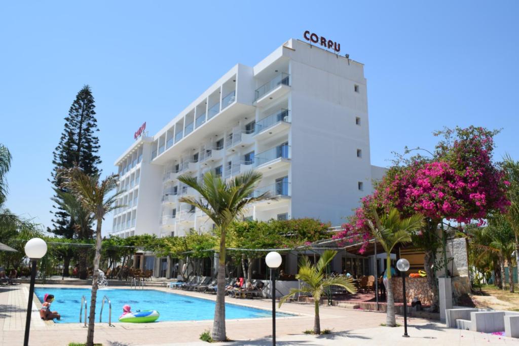 a hotel with a swimming pool in front of a building at Corfu Hotel in Ayia Napa