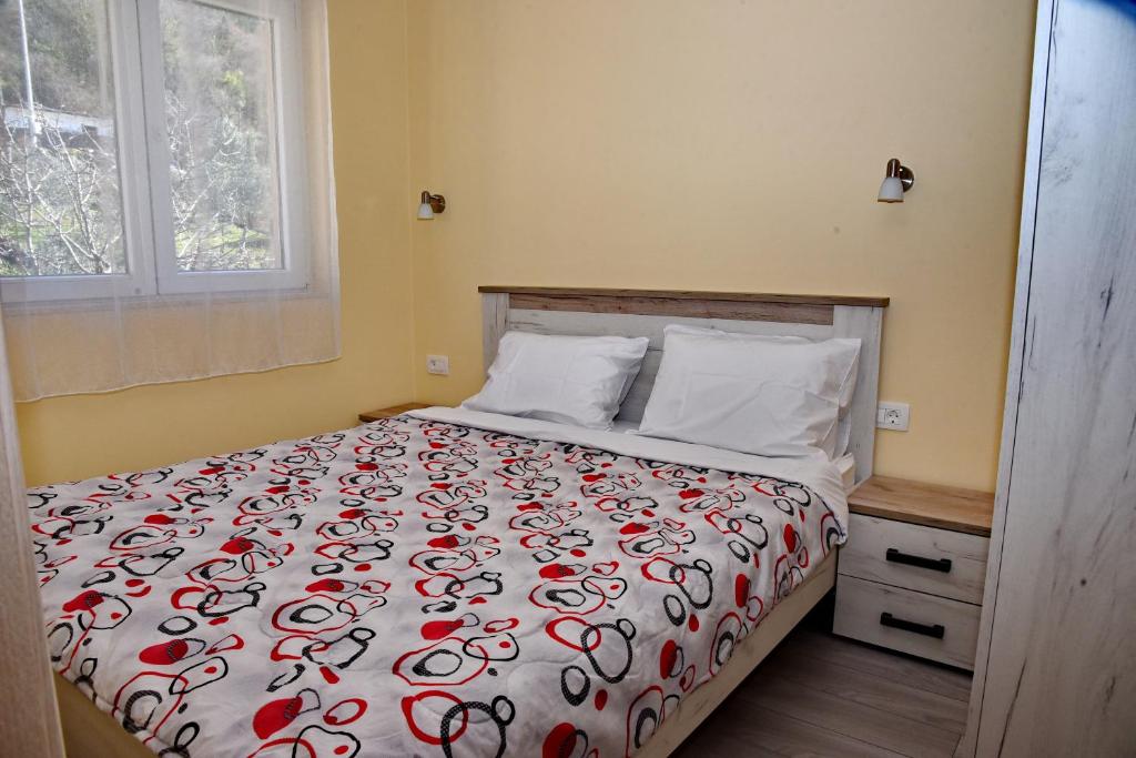 a bedroom with a bed with a red and white comforter at Sunset Apartments in Kotor