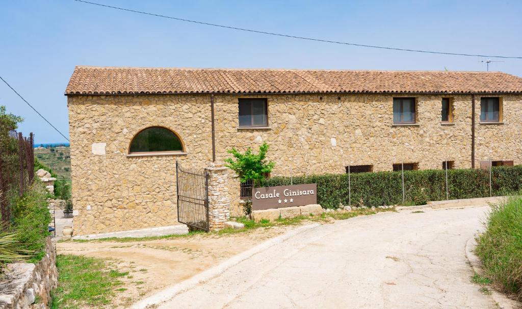 un edificio in pietra con un cancello di fronte di Casale Ginisara a Castellammare del Golfo