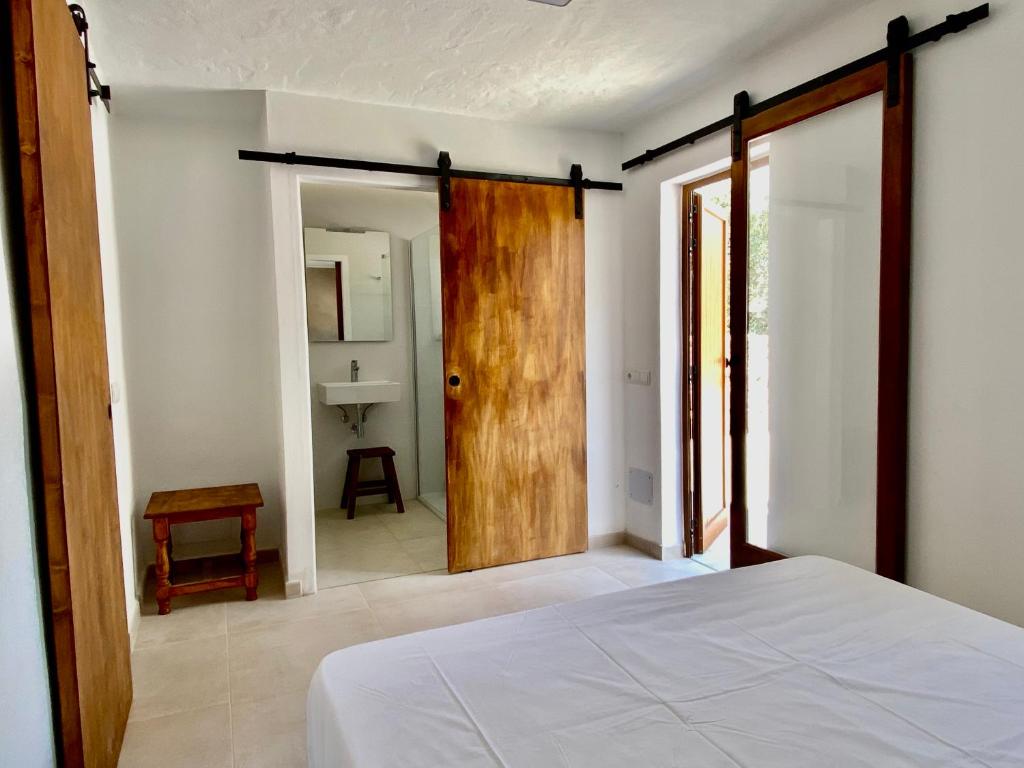 a bedroom with a bed and a door to a bathroom at Agradable casa rural en zona reserva natural. in Sant Francesc Xavier