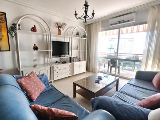 een woonkamer met een blauwe bank en een tafel bij Apartamento la Fragata Nerja in Nerja