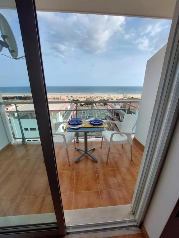 Un balcón con mesa y sillas y el mar. en À da Mamé - Monte Gordo, en Monte Gordo