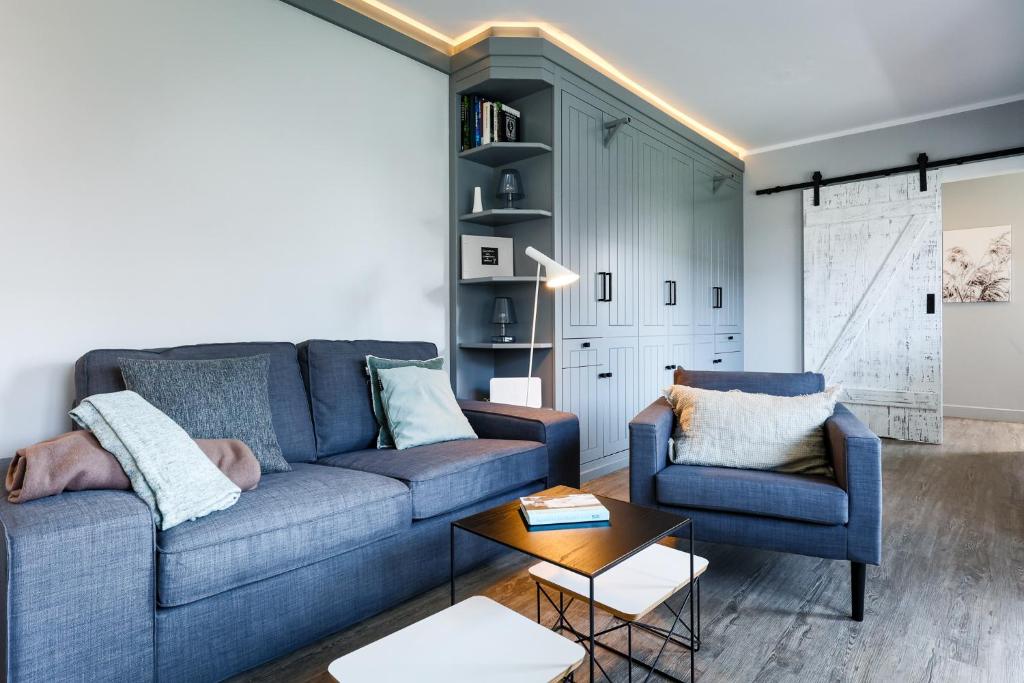 sala de estar con sofá azul y 2 sillas en StefansPlatz en Hörnum