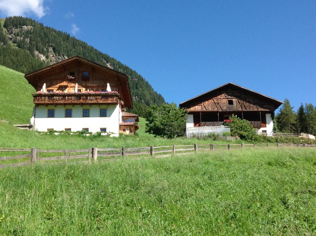 two buildings in a field next to a fence at Biohof Hamann in Sarntal