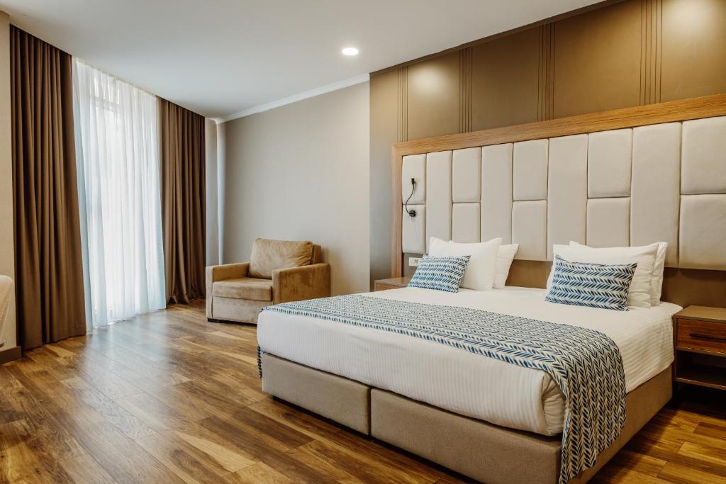 King Solomon Batumi Hotel في باتومي: غرفة نوم بسرير كبير وكرسي