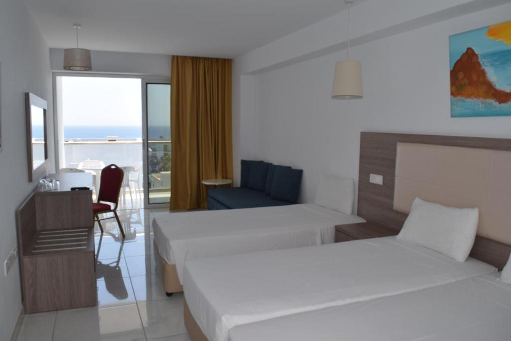 a hotel room with two beds and a chair at Corfu Hotel in Ayia Napa