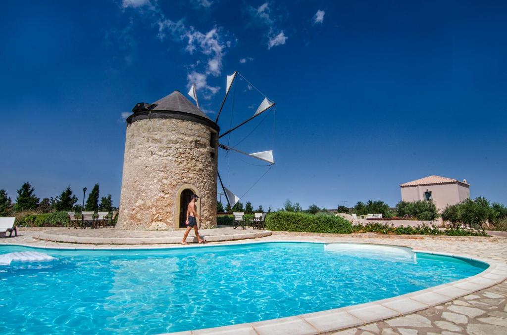 a woman walking in front of a windmill at The Windmill Resort in Mitáta