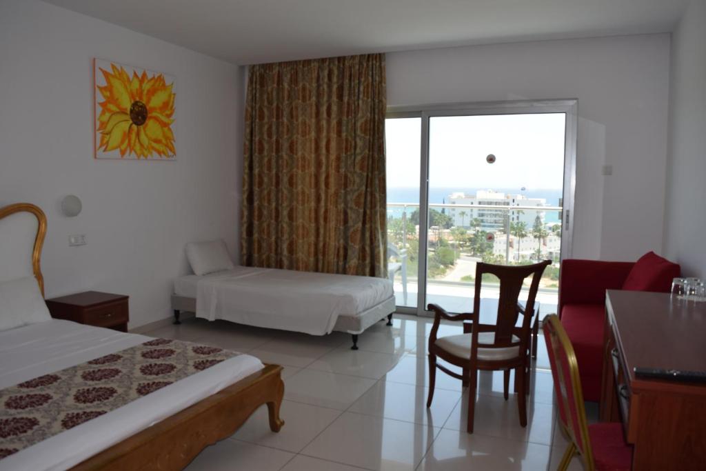 a hotel room with a bedroom with a bed and a window at Corfu Hotel in Ayia Napa