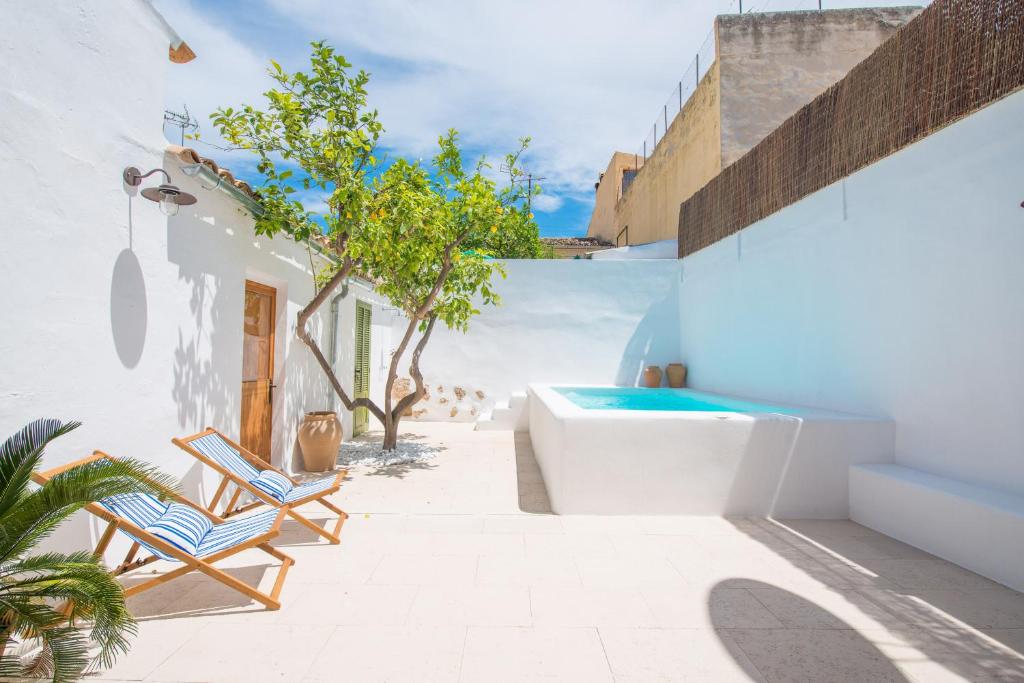 Casa blanca con patio con bañera y sillas en Ca Na Mandola, en Alaró