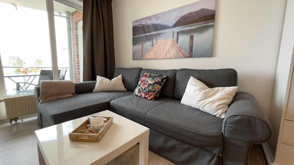 ein Wohnzimmer mit einem Sofa und einem Tisch in der Unterkunft Strandhaus Nordseebrandung Fewo B1.4 in Cuxhaven