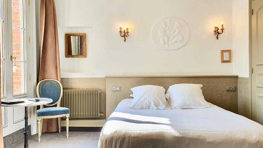 a bedroom with a bed and a table and a chair at Les Cabines in Houlgate