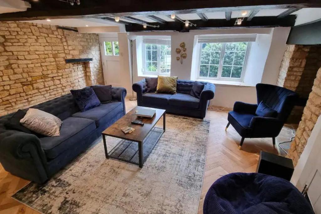 - un salon avec des canapés et des chaises ainsi qu'un mur en briques dans l'établissement Pass the Keys Charming 18th Century 4 bedroom cottage, à Moreton-in-Marsh