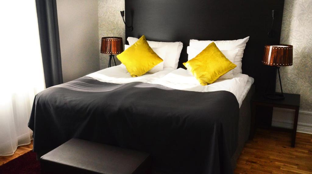 Clarion Collection Hotel Plaza في كارلشتاد: سرير كبير عليه وسادتين صفراء