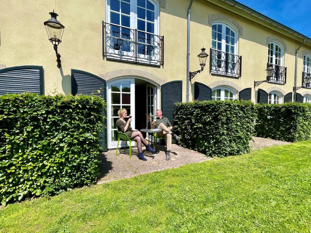 twee mensen aan een tafel voor een gebouw bij Hotel & Restaurant - Auberge De Hilver in Diessen