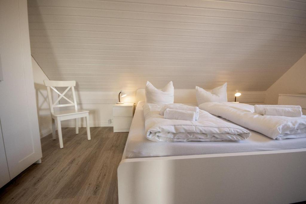 ein Bett mit zwei Kissen und einem Stuhl in einem Zimmer in der Unterkunft Ferienwohnung 'Haus Ingeborg, Wohnung 1/EG' in Cuxhaven