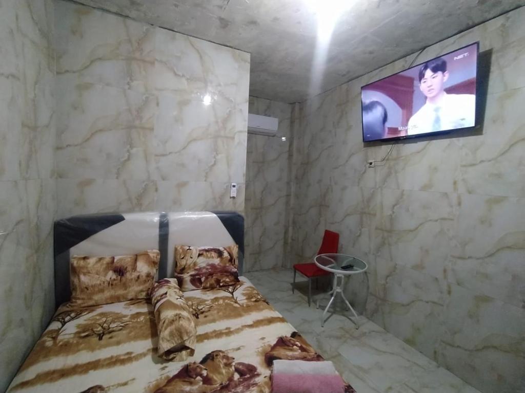 Schlafzimmer mit einem Bett und einem TV an der Wand in der Unterkunft Near Grosir Stono 2 in Pekalongan
