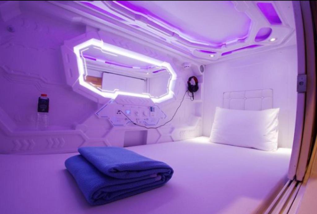 a small room with a bed and a light at Super OYO 91328 Fiducia Capsule Hotel in Jakarta