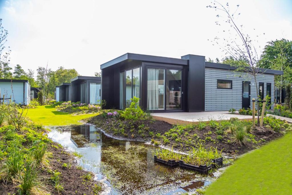 a modular home with a garden and a creek at EuroParcs De Wiedense Meren in Wanneperveen