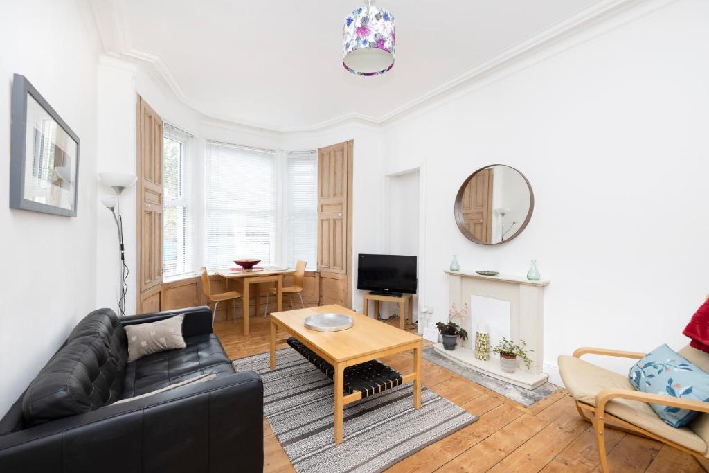 a living room with a couch and a table at ALTIDO Charming 1-bed ap near Leith Links w/ patio in Edinburgh