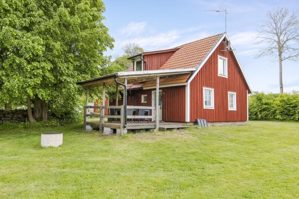 un granero rojo con porche y patio en Cozy cottage at Bolmstad Sateri by Lake Bolmen, en Ljungby