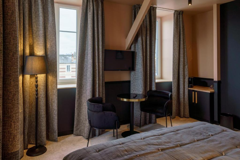 a hotel room with a bed and chairs and a window at Hotel de la Plage in Lion-sur-Mer