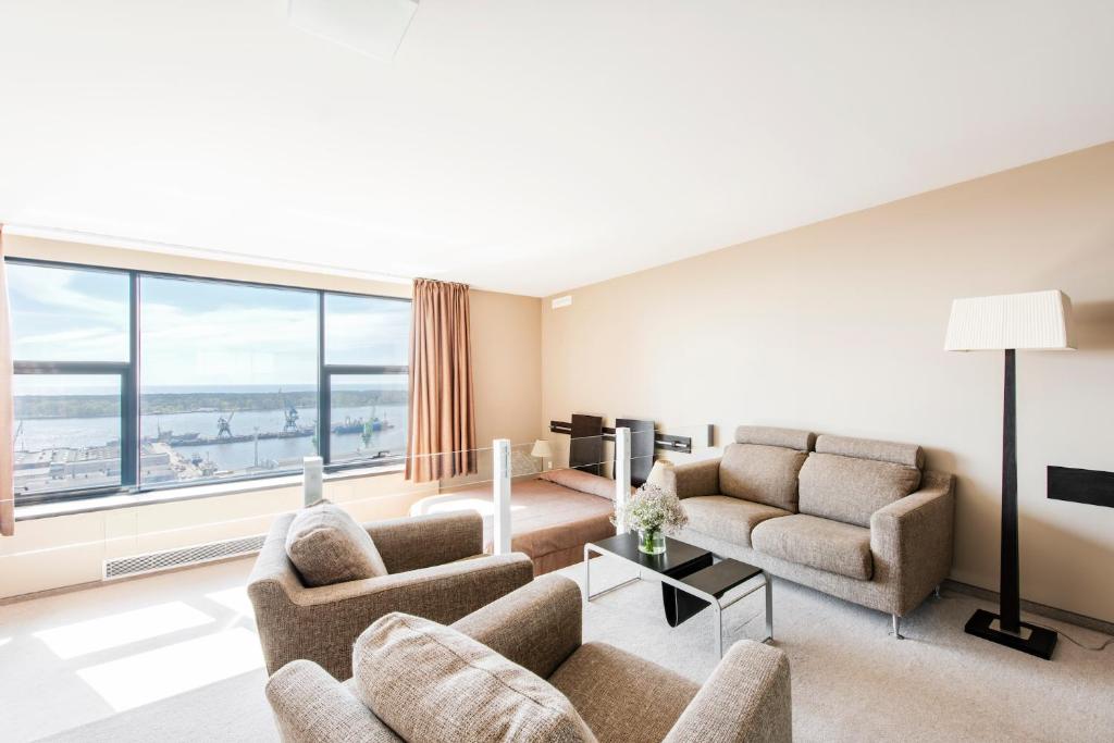 a living room with two couches and a large window at Amberton Hotel Klaipeda in Klaipėda