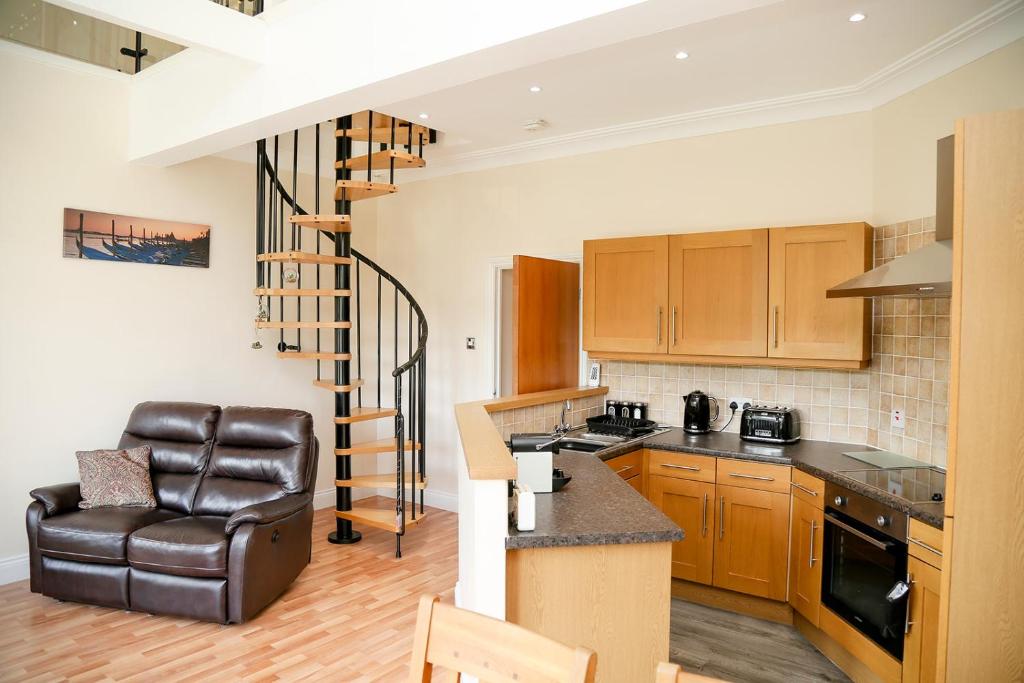 a kitchen with a couch and a chair in a room at Beautiful cozy 3 bedroom 2 bathroom apartment in Newcastle upon Tyne