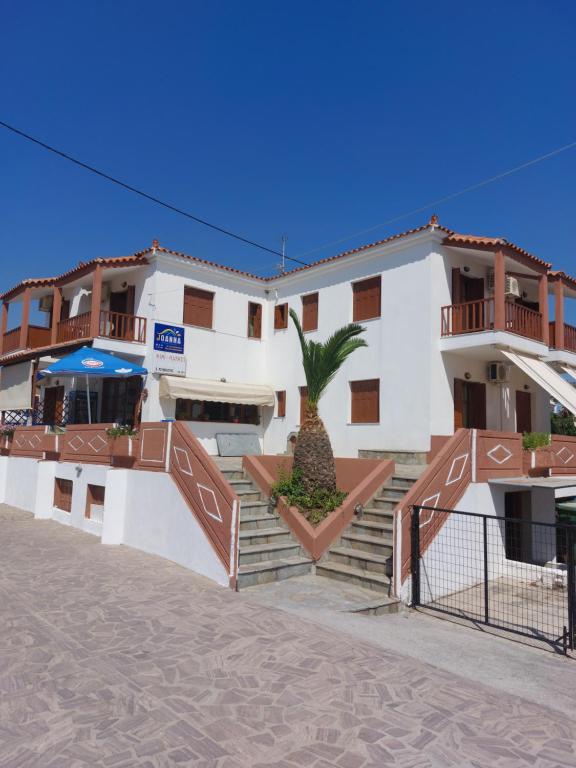 un edificio con una palmera delante de él en Joanna Rooms, en Skala Eresou