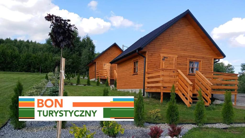 two wooden houses with a sign in front of them at Agroturystyka Sosenka in Bieliny