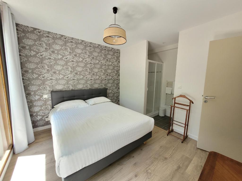 - une chambre avec un lit blanc et un mur dans l'établissement L'Appartement des Esclargies, à Rocamadour