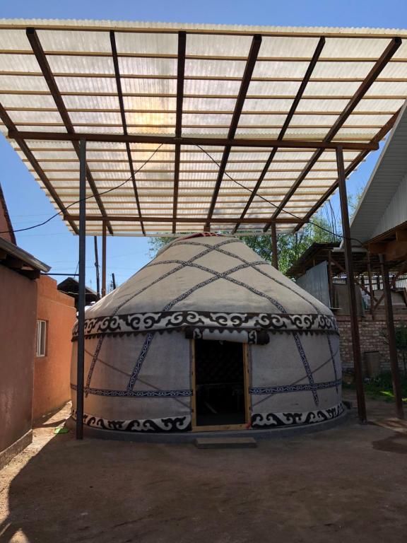 a large yurt with a wooden door under a roof at Guest House Baiel in Bokonbayevo