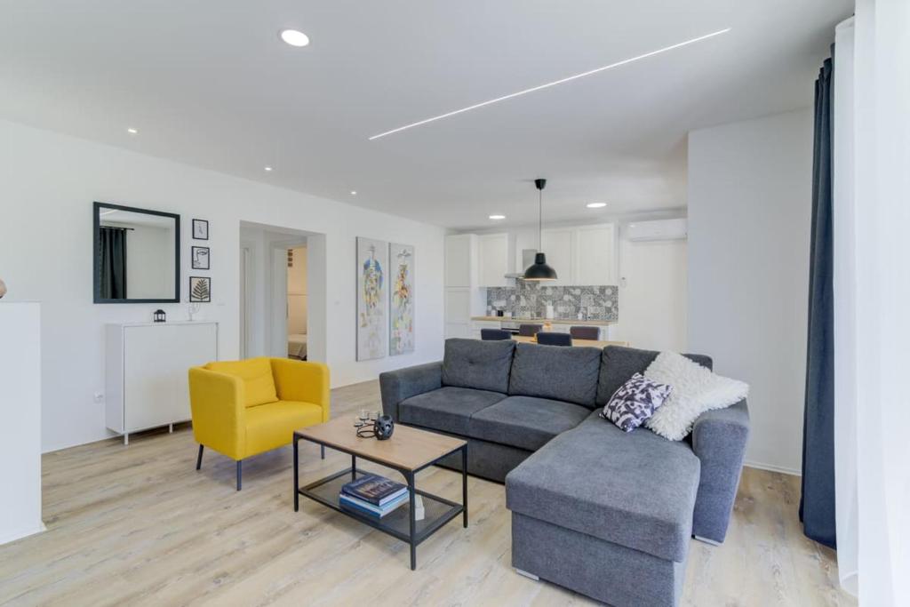 a living room with a blue couch and a yellow chair at NV Sun 23 by Aneo Travel in Novi Vinodolski