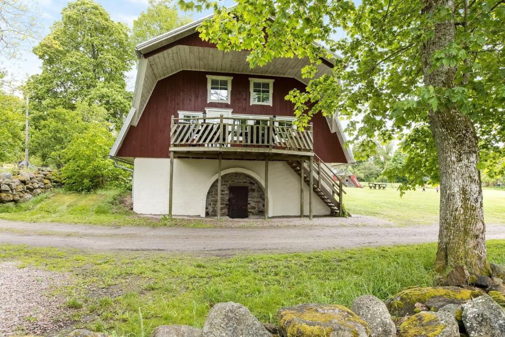 um grande celeiro vermelho com uma varanda e uma árvore em Large holiday house with lake view of Bolmen em Ljungby