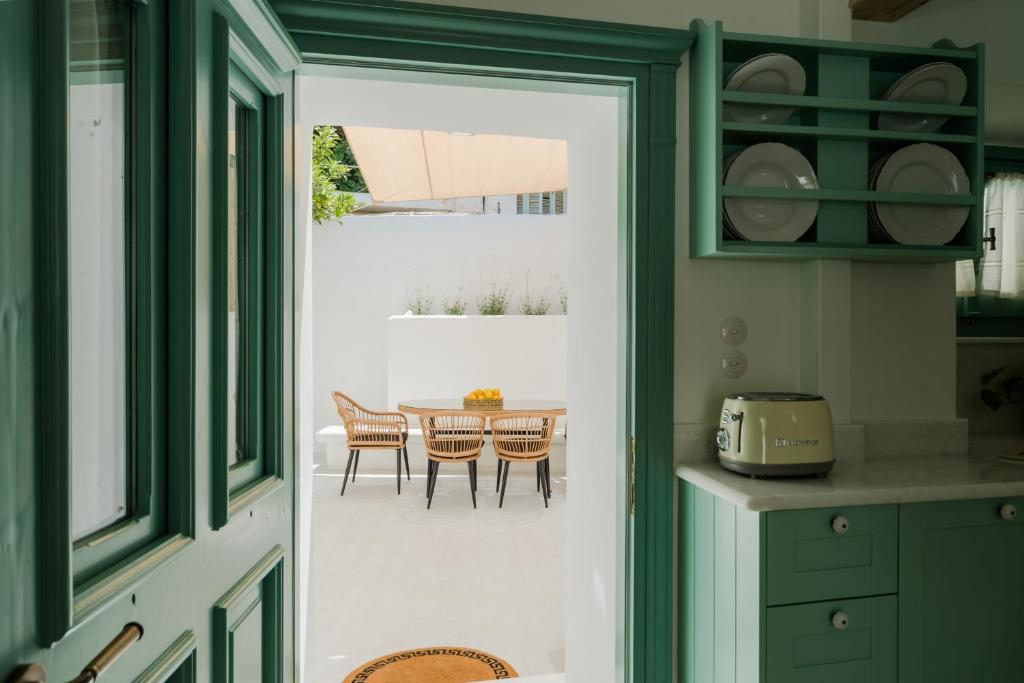 kuchnia z zielonymi szafkami i stołem z krzesłami w obiekcie La Casa Degli Archi w mieście Kos