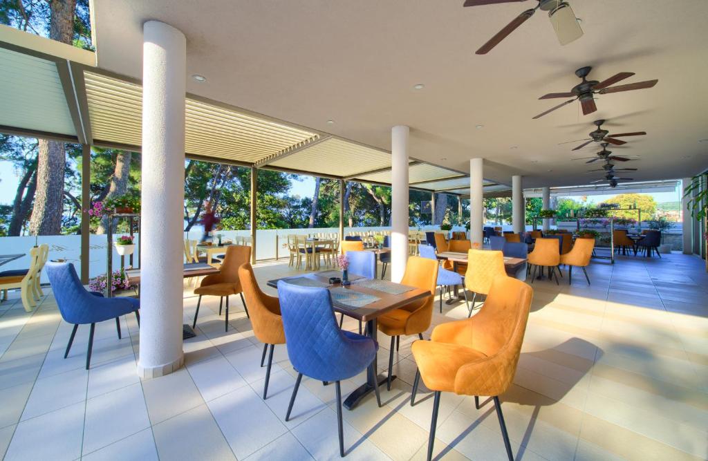 a restaurant with blue chairs and tables and windows at Hotel Bor in Krk